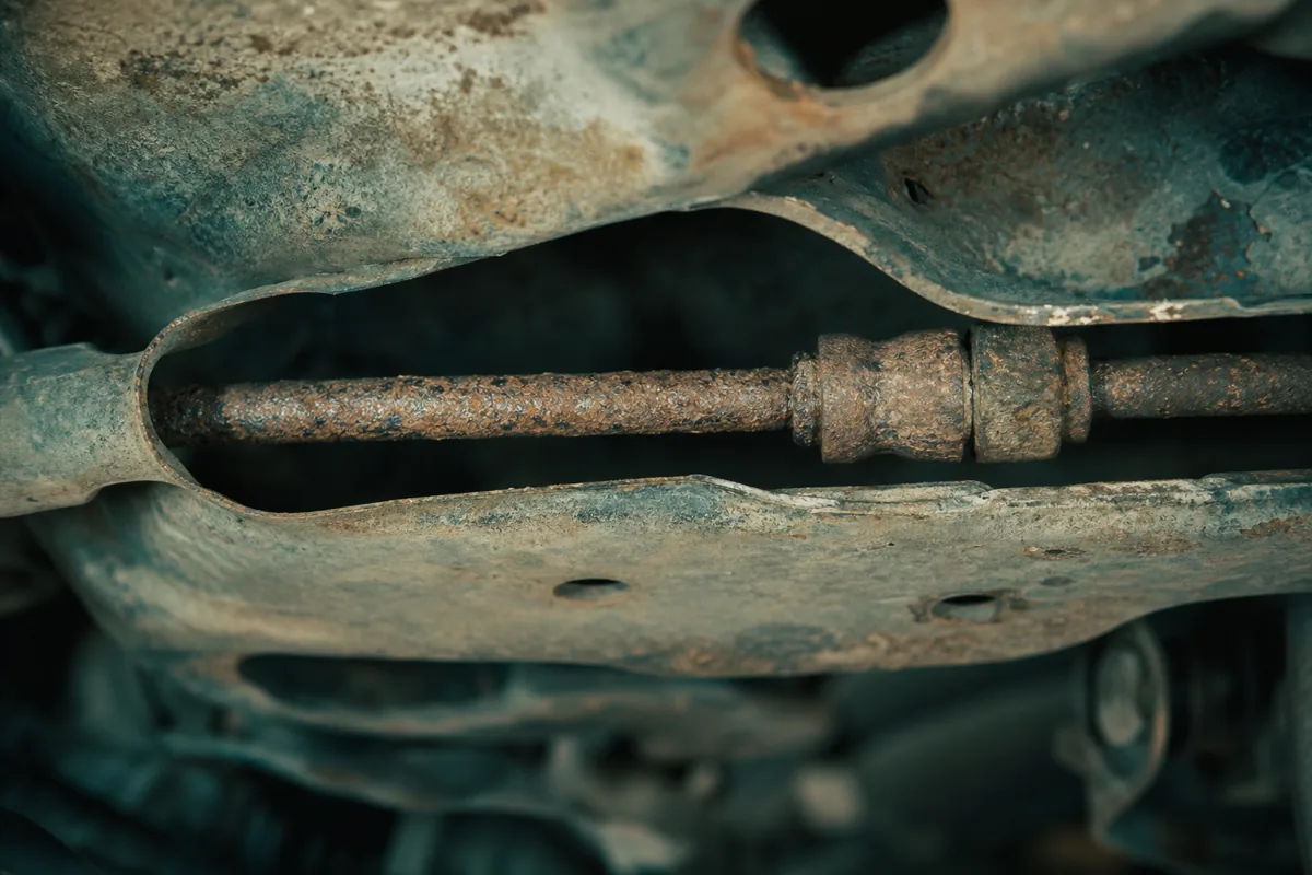 Corroded brake hard line section routed through a vehicle subframe channel during hidden inspection, 1200x800